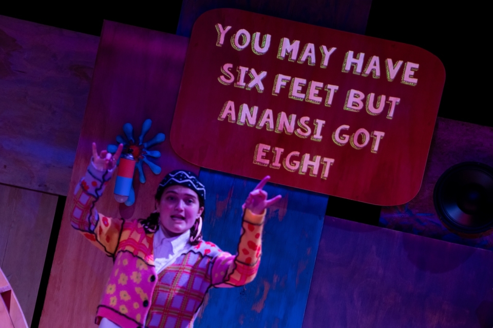 Actor Sophie Bagheri, who plays Ah-ight, appears in front of a caption with a character-specific font and color palette in "Hip Hop Anansi."