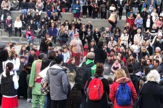 A crowd of people gathered in a city square to watch a performance.