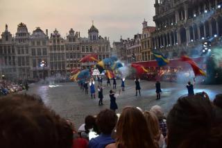 Performers throw flags into the air during a performance in a city courtyard.