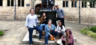 A group of students pose next to a statue for a picture.